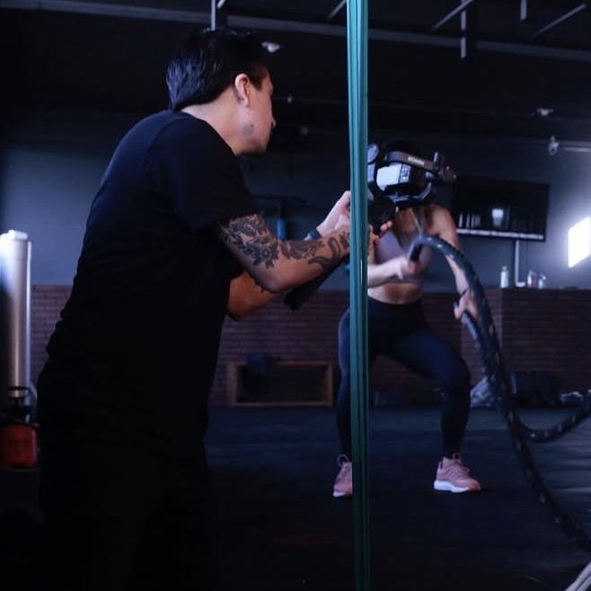 Juan Fernando grabando con cámara en mano una sesión de entrenamiento en un gimnasio